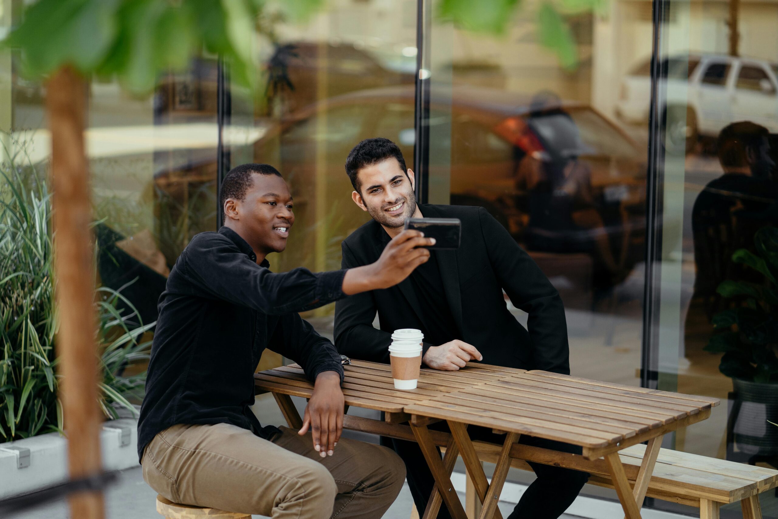 Two people meeting outdoors at a cafe, taking a photo together