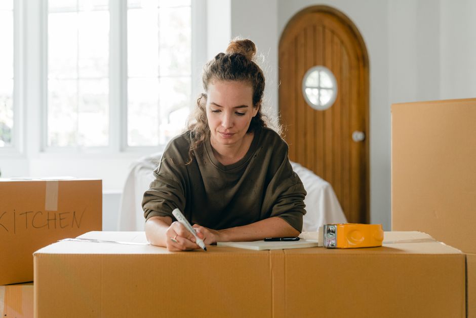Person writing on a moving box while planning a home move