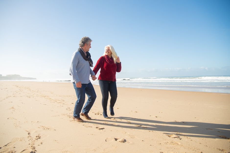 Two older adults walking together on a beach
