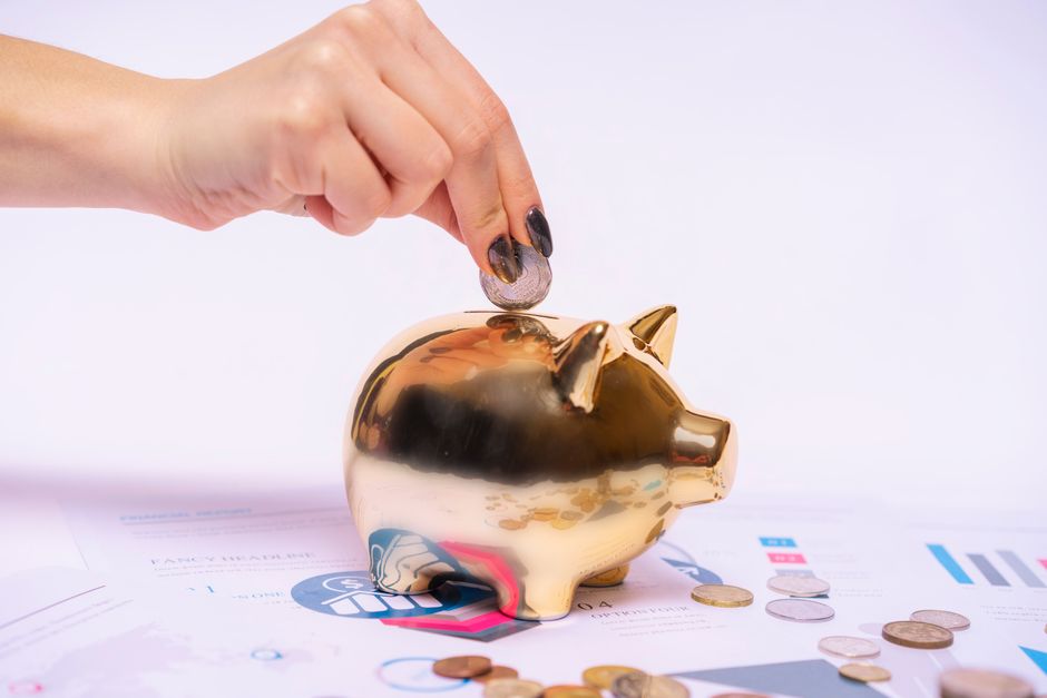 Hand placing a coin in a piggy bank on financial papers