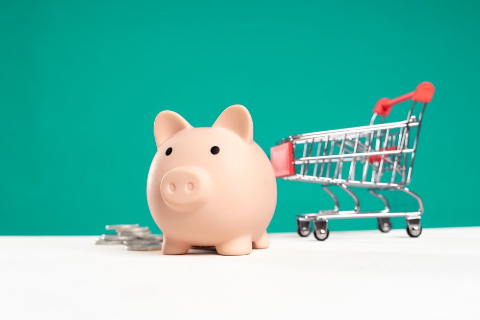 Piggy bank beside a small shopping trolley on a table