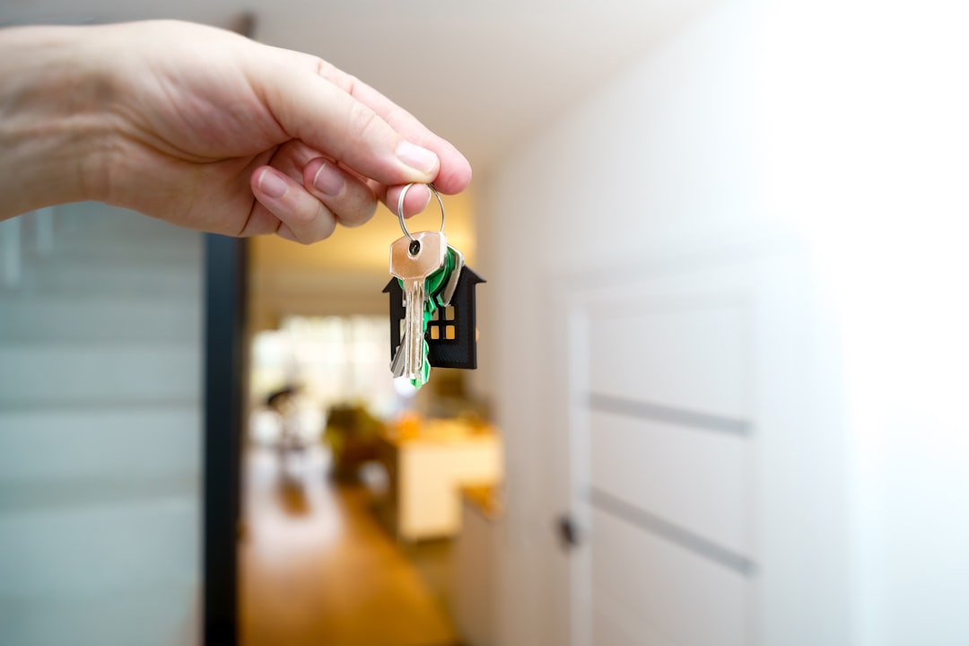 Hand holding house keys at an apartment entrance