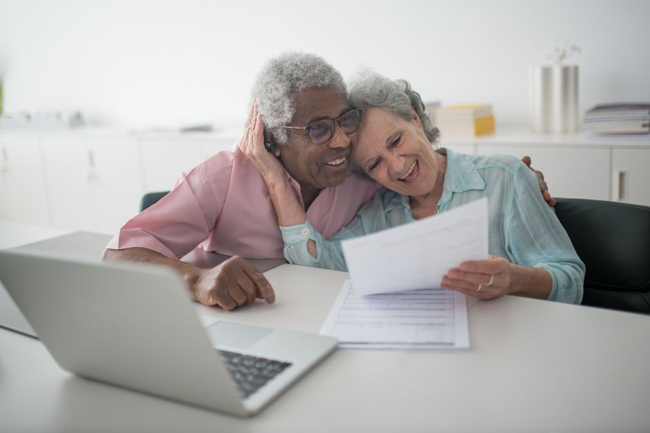 Two people reviewing paperwork beside a laptop